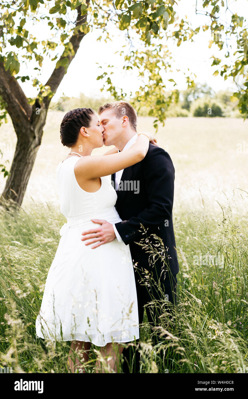 Schwangere Braut küssen ihr Mann auf einer Wiese Stockfoto