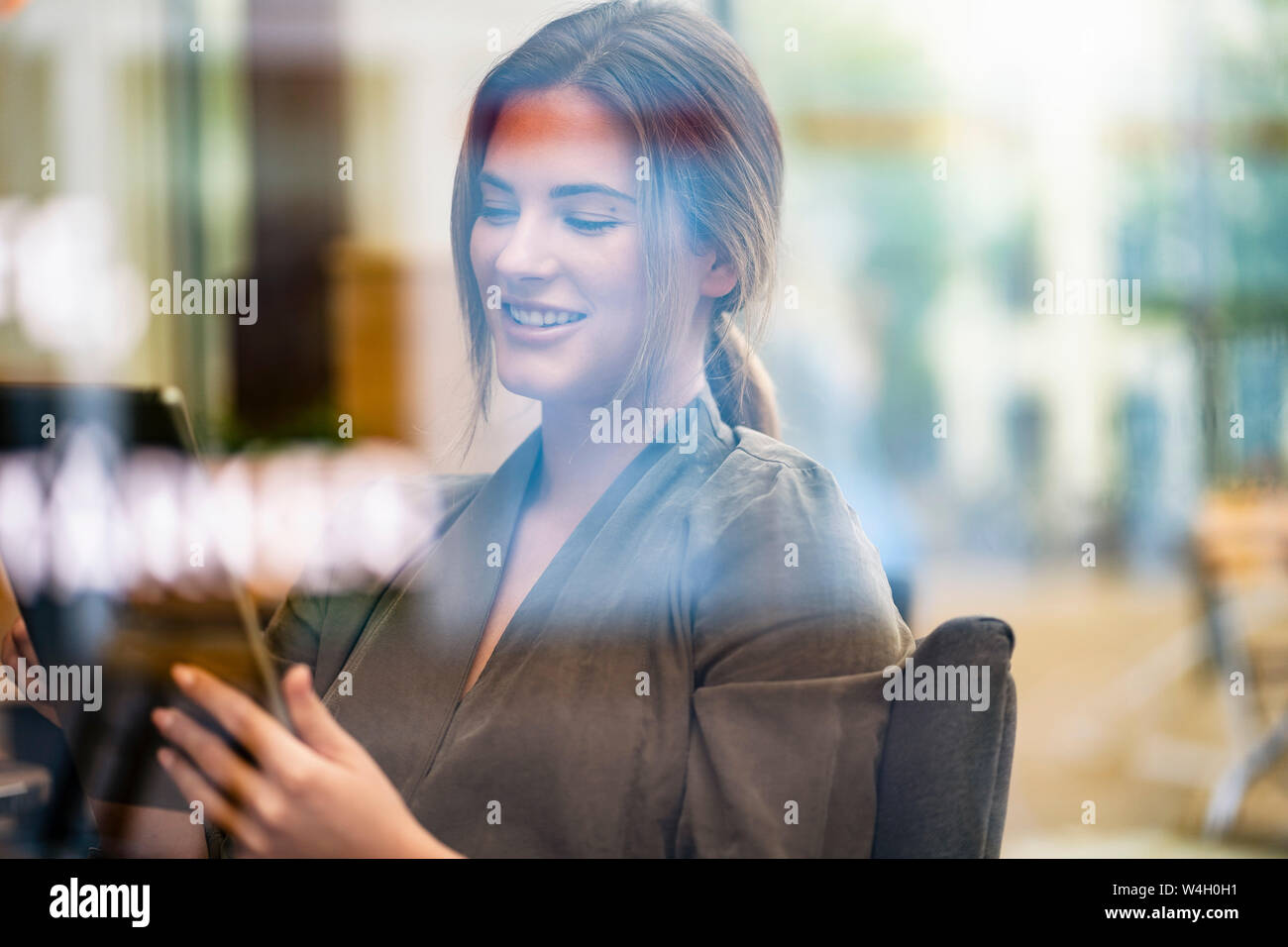 Junge Geschäftsfrau mit Tablette in ein Café, durch das Fenster gesehen Stockfoto
