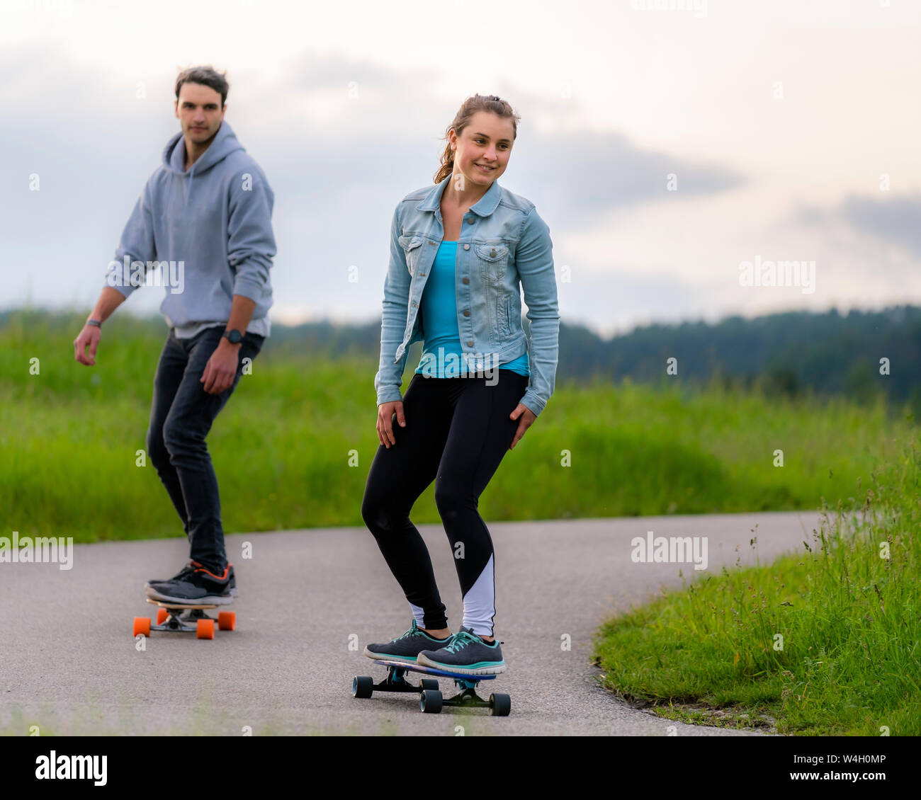 Junge Frauen und junge Männer reiten Longboard Stockfoto