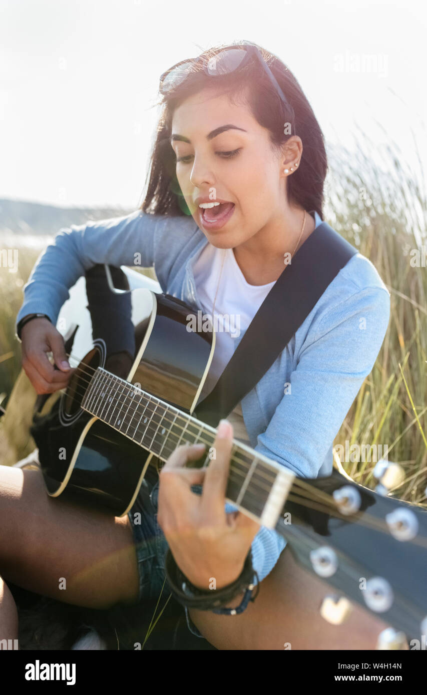 Junge Frau singen und Gitarre spielen am Strand Stockfotografie - Alamy