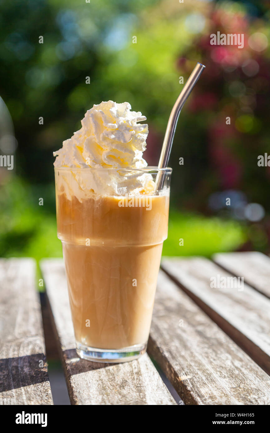 Glas Eiskaffee mit Sahne Topping auf Garten Tisch Stockfoto