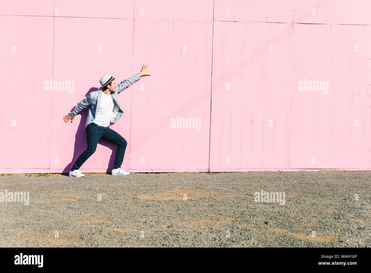 Junger Mann vor rosa Bau Barriere, Gefühl gefangen Stockfoto