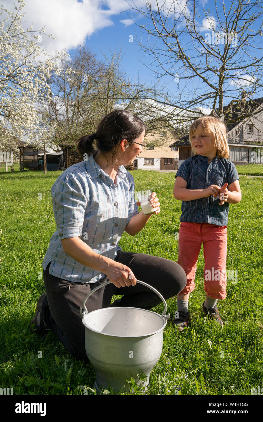 Mutter und Tochter mit frischer Milch in einem Eimer auf der Weide Stockfoto