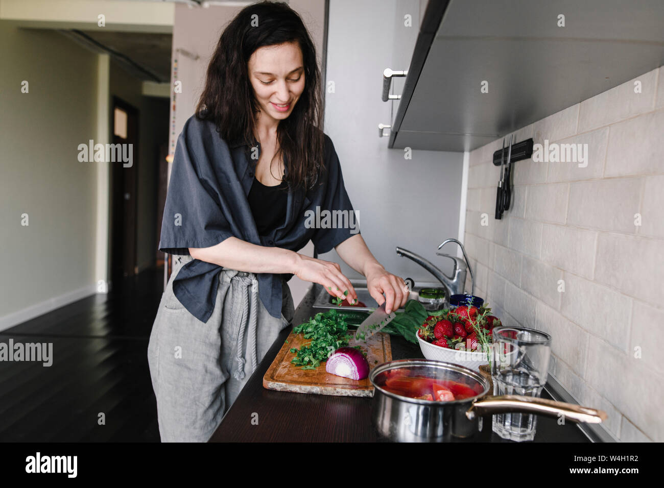 Lächelnde Frau bereitet Salat in der Küche Stockfoto