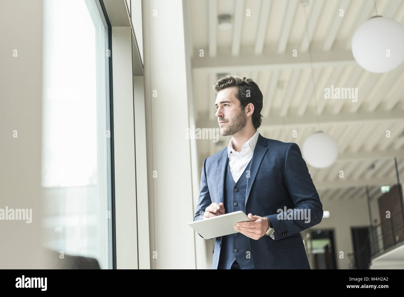 Erfolgreiche Manager stehen in der modernen Bürogebäude, mit Laptop, Blick aus Fenster Stockfoto