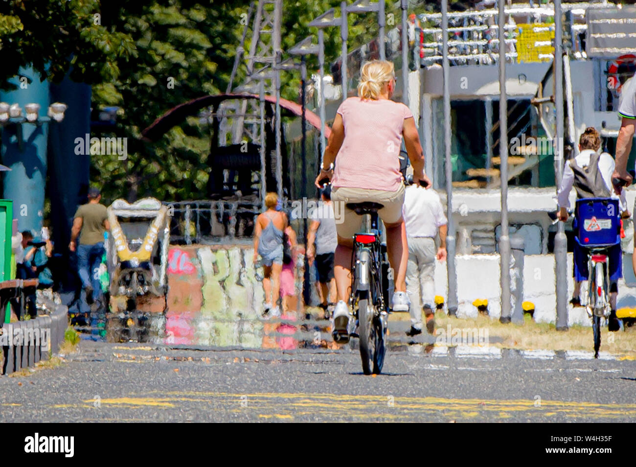 23 Juli 2019, Hessen, Frankfurt/Main: Radfahrer und Fußgänger sind auf dem Weg entlang der Hauptstraße. Auf dem heißen Asphalt wird die Luft in der Ferne wider. Foto: Frank Rumpenhorst/dpa Stockfoto