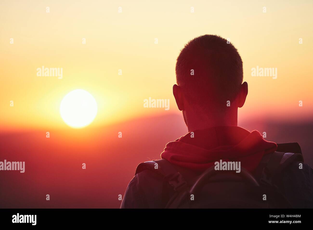Ansicht der Rückseite des jungen Mann gegen Berg stehend bei Sonnenuntergang. Stockfoto