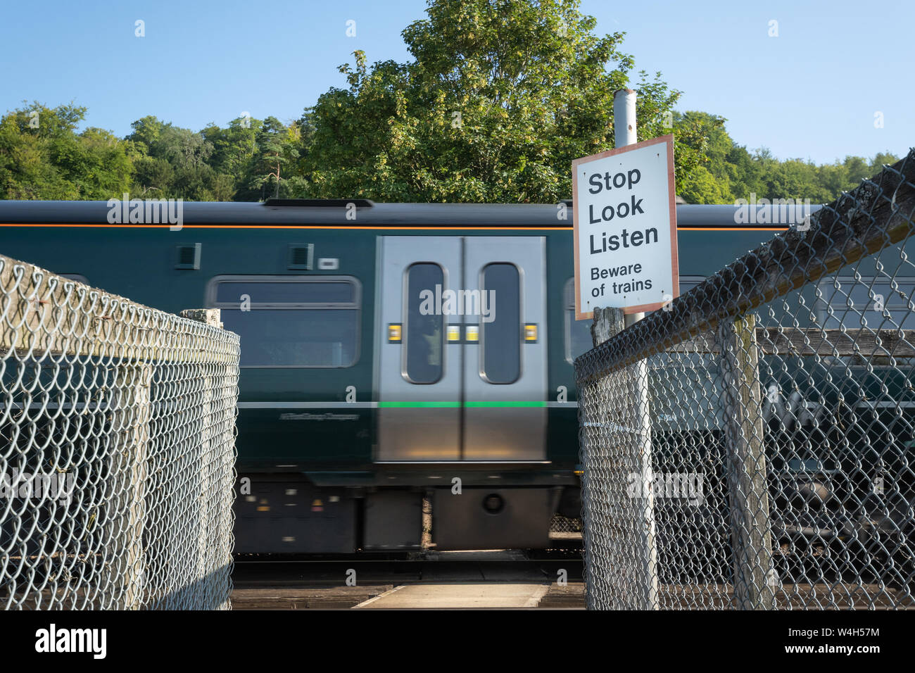 Pfad Überqueren einer Eisenbahnstrecke mit einem vorbeifahrenden Zug mit einer Sicherheits-Warnzeichen, Stop Look Listen, passen von Zügen, Großbritannien Stockfoto Pfad Überqueren einer Eisenbahnstrecke mit einem vorbeifahrenden Zug mit einer Sicherheits-Warnzeichen, Stop Look Listen, passen von Zügen, Großbritannien Stockfoto