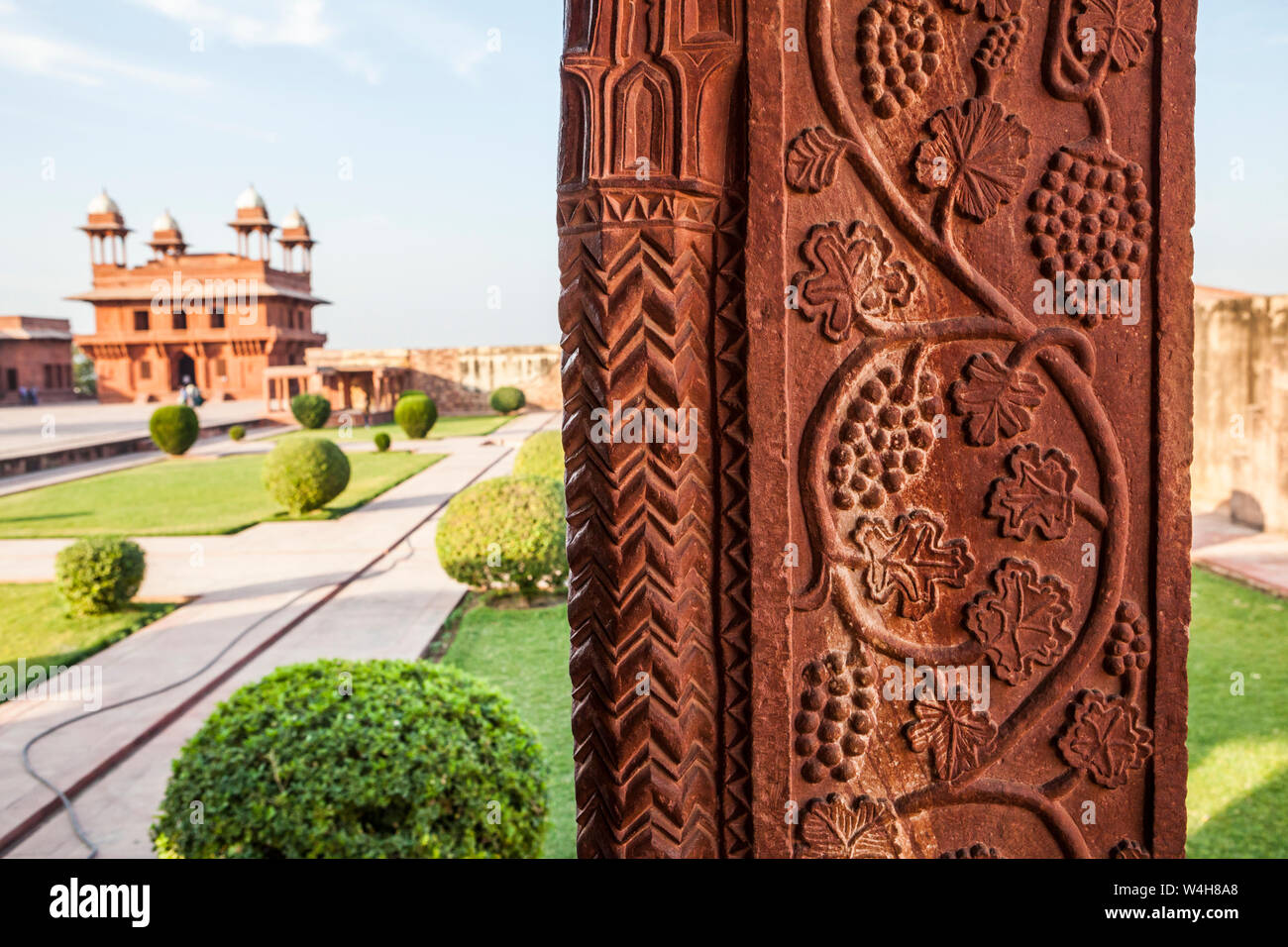 Ein Innenhof in der Wüstenstadt Fatehpur Sikri Komplex mit Detail aus Stein gehauene Säule im Vordergrund. Stockfoto