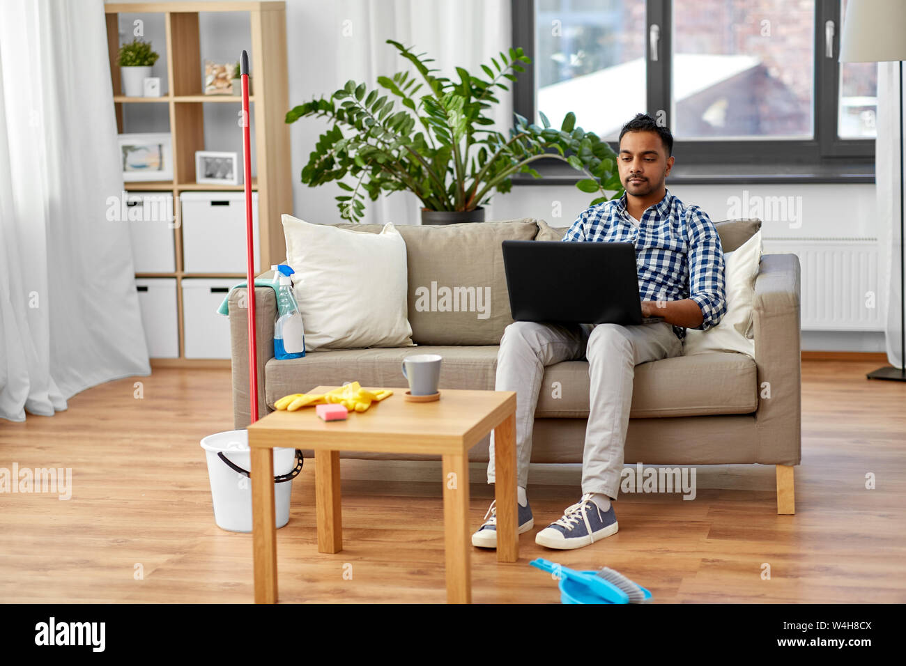 Mann mit Laptop nach Hause Reinigung Stockfoto