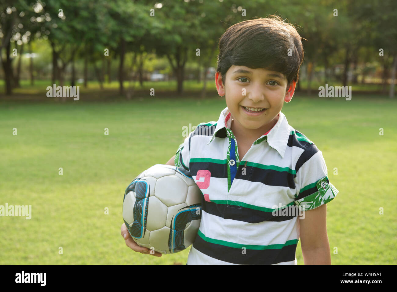 Bildnis eines Knaben halten einen Fußball und lächelnd Stockfoto