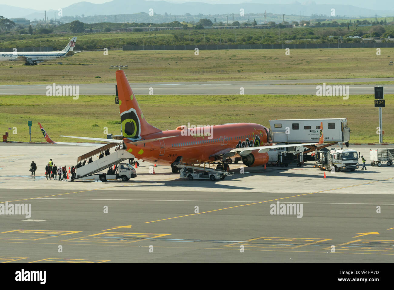 Low cost budget Südafrikanischen Fluggesellschaft, Mango Airlines, auf dem Rollfeld laden Passagiere oder Leute an den Internationalen Flughafen Kapstadt, Südafrika Stockfoto