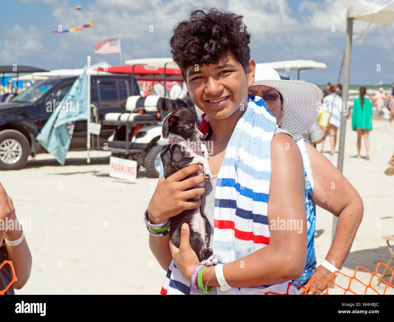 Ein Junge mit dunklen, lockiges Haar hat einen schwarzen und weißen Chihuahua Am2019 Texas Sandfest in Port Aransas, Texas USA. Stockfoto