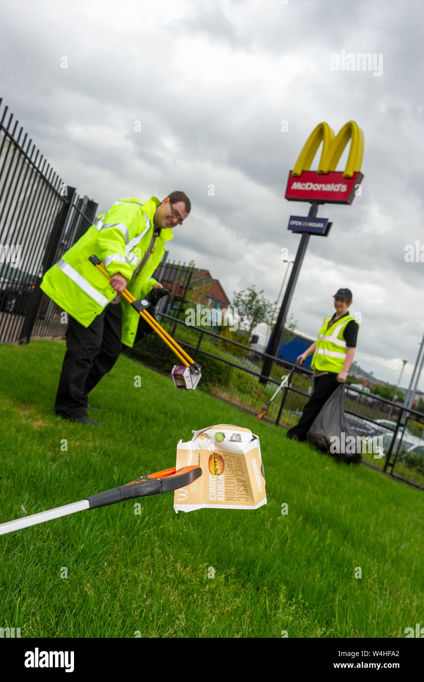 Nahaufnahme von Wurf picker Holding fast food Verpackung mit zwei Personen und einem McDonalds Schild im Hintergrund Stockfoto