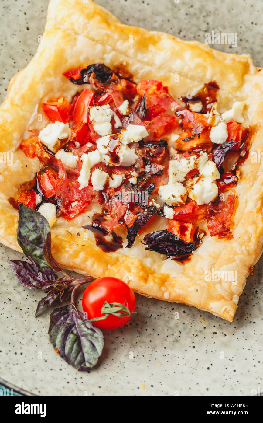 Blätterteig Törtchen mit Tomaten, süßer Paprika, Salami, Fetakäse und lila Basilikum. Ansicht von oben. Close Up. Stockfoto