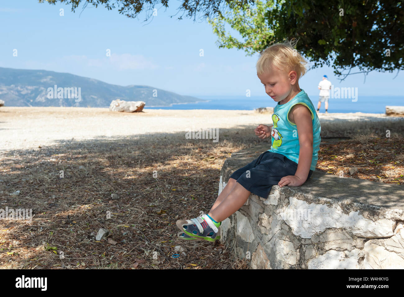 Zwei Jahre alten Sohn auf einem Felsen in der Nähe von Agrilion Monasetery in der Nähe von Sami, Kefalonia, Ionische Inseln, Griechenland, Europa sitzen Stockfoto