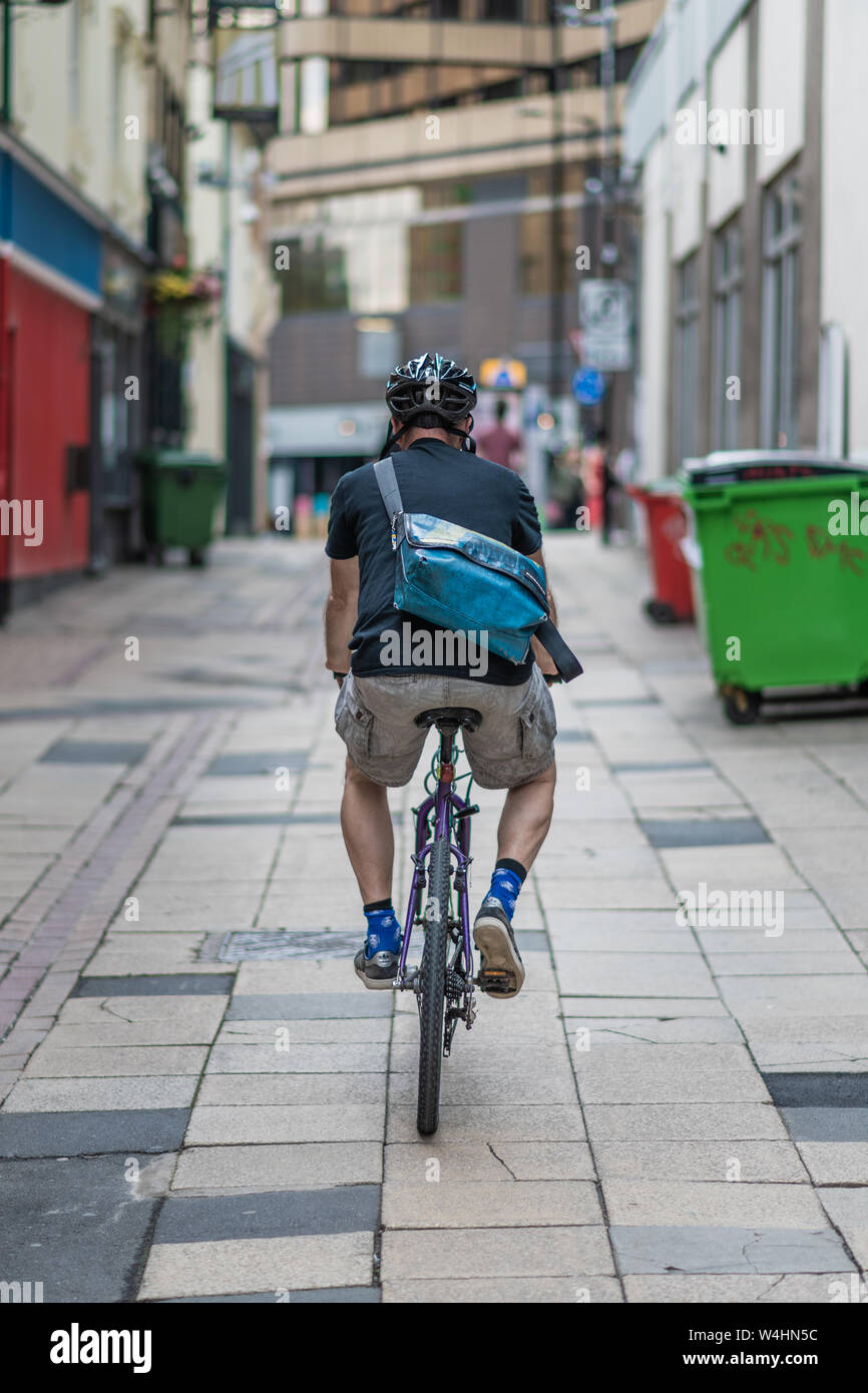 Männliche Radfahrer mit Helm auf Fahrten durch eine Gasse in Sheffield City Centre Stockfoto