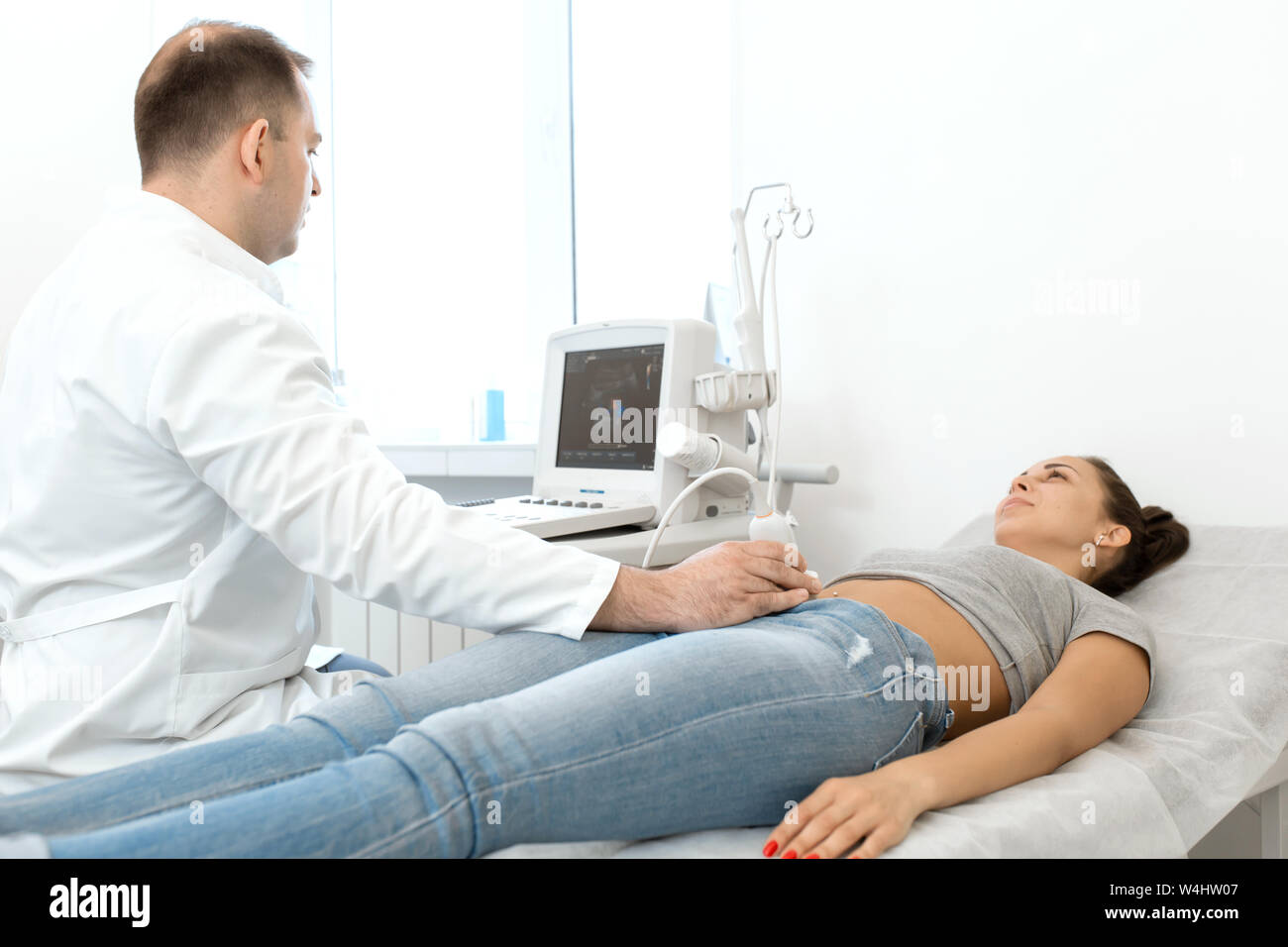 Junge Frau in 4D Ultraschall. Die Ultraschalldiagnostik, die Untersuchung des Abdomens. Stockfoto