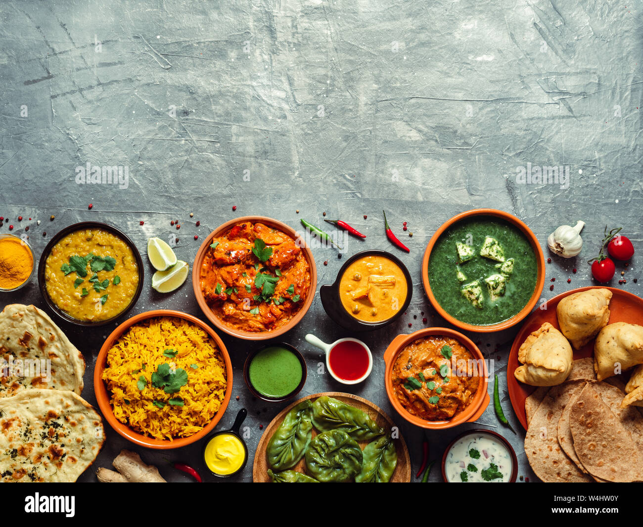 Indische Küche Gerichte: Tikka Masala, dal, Paneer, Samosa, chapati, Chutney, Gewürze. Indische Küche auf grauem Hintergrund. Sortiment indische Mahlzeit mit Kopie Platz für Text. Top View oder flach. Stockfoto