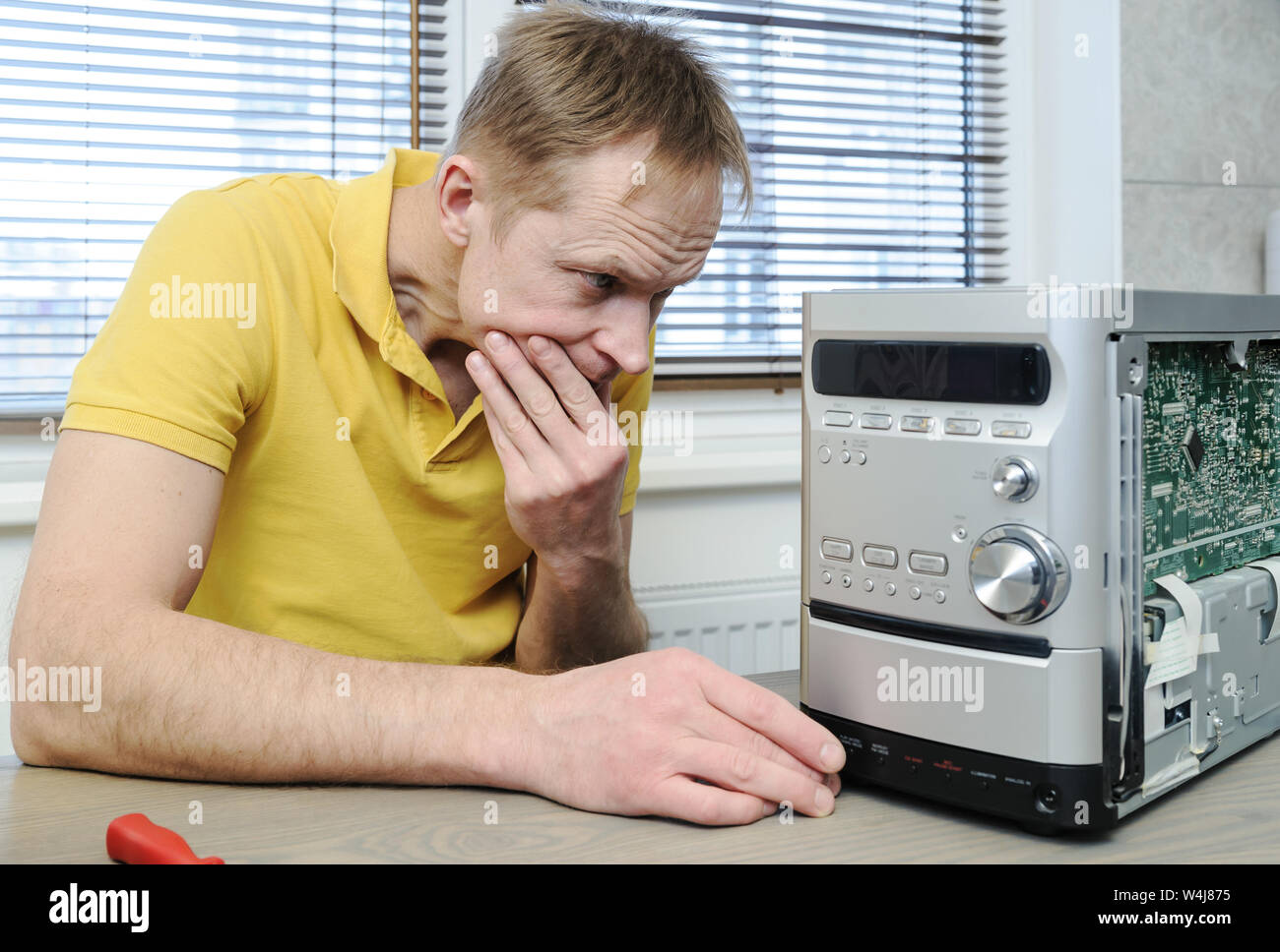 Ein Mann ist die Instandsetzung der musikalischen System. Er ist auf der Suche innerhalb des Gerätes. Stockfoto