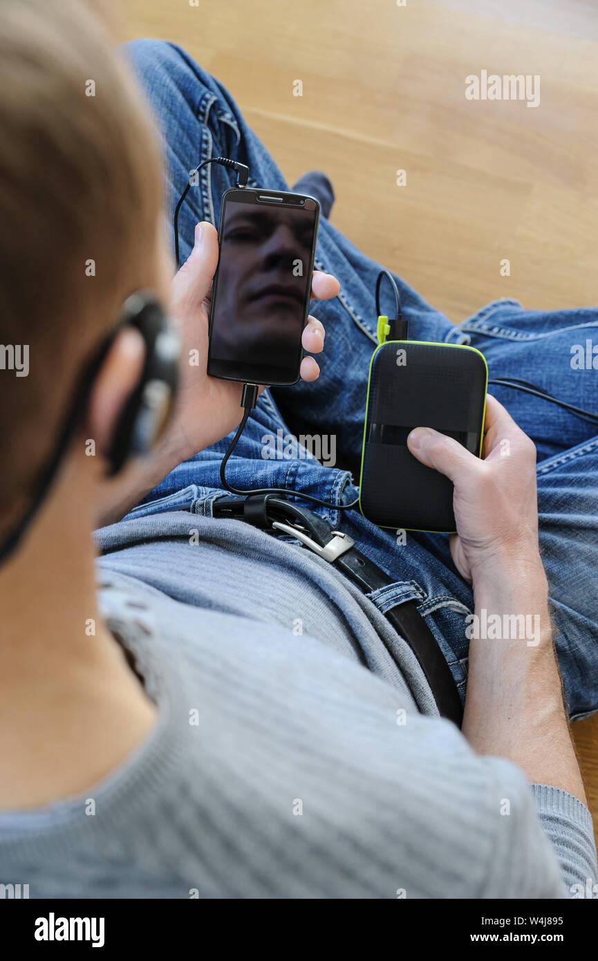 Der Mann hält ein Smartphone und eine Bank. Er ist das Hören von Musik. Ansicht von oben. Stockfoto