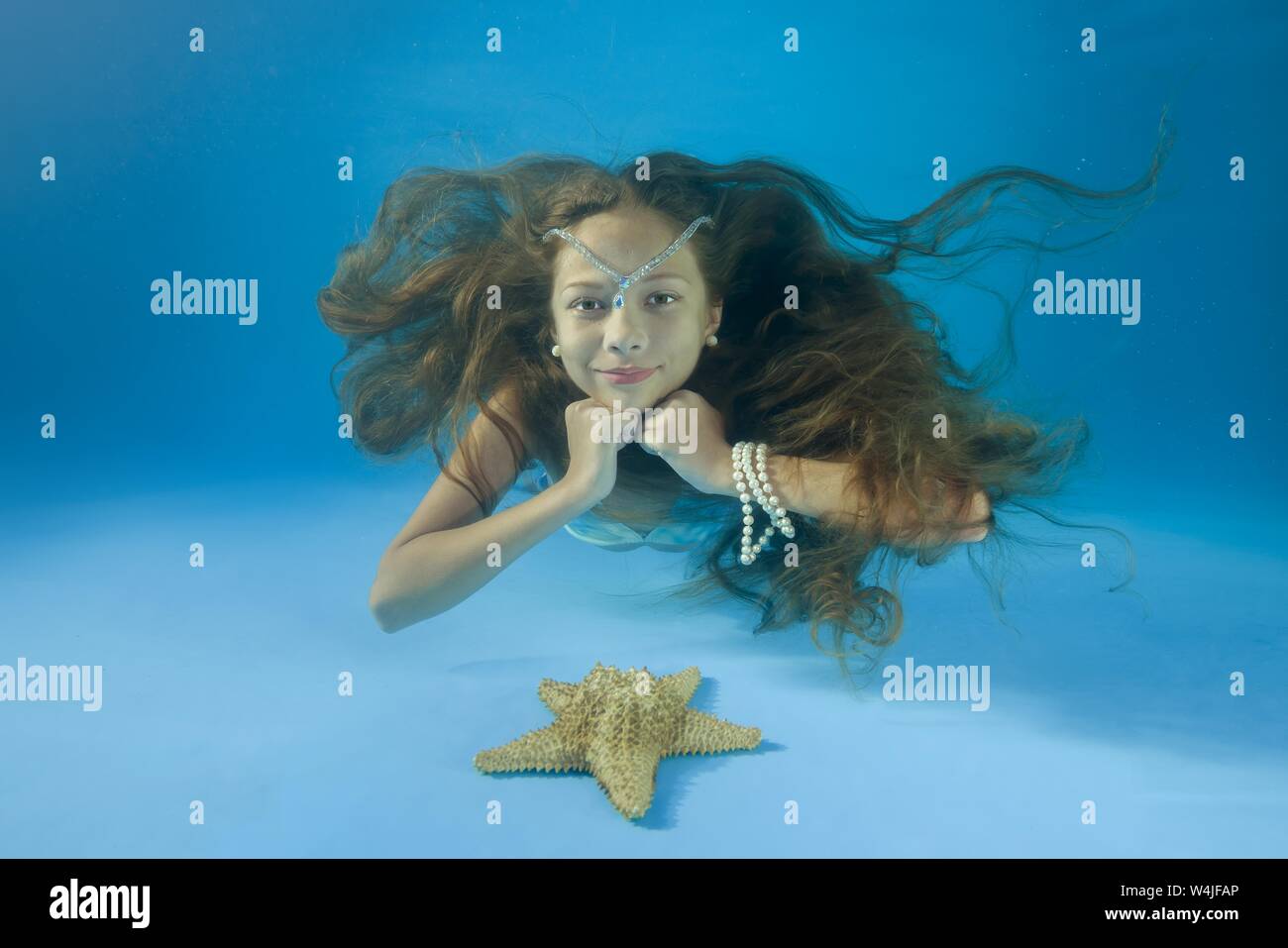 Mädchen mit log Haare und Seestern Unterwasser, Odessa, Ukraine Stockfoto