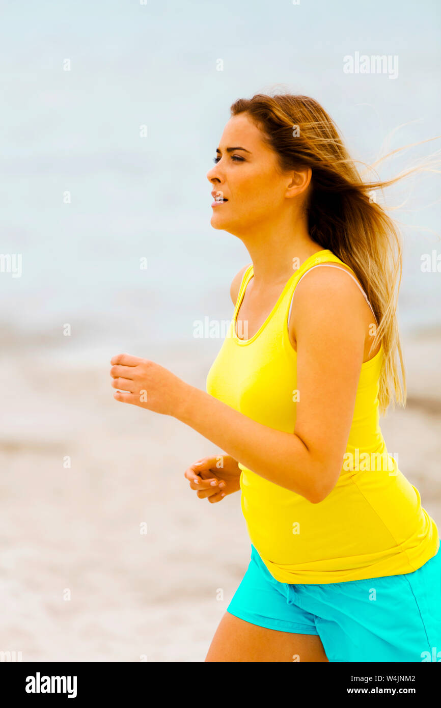 Frau in Sportbekleidung laufen am Strand. Aktiver Lebensstil. Sport im Freien auszuüben. Stockfoto