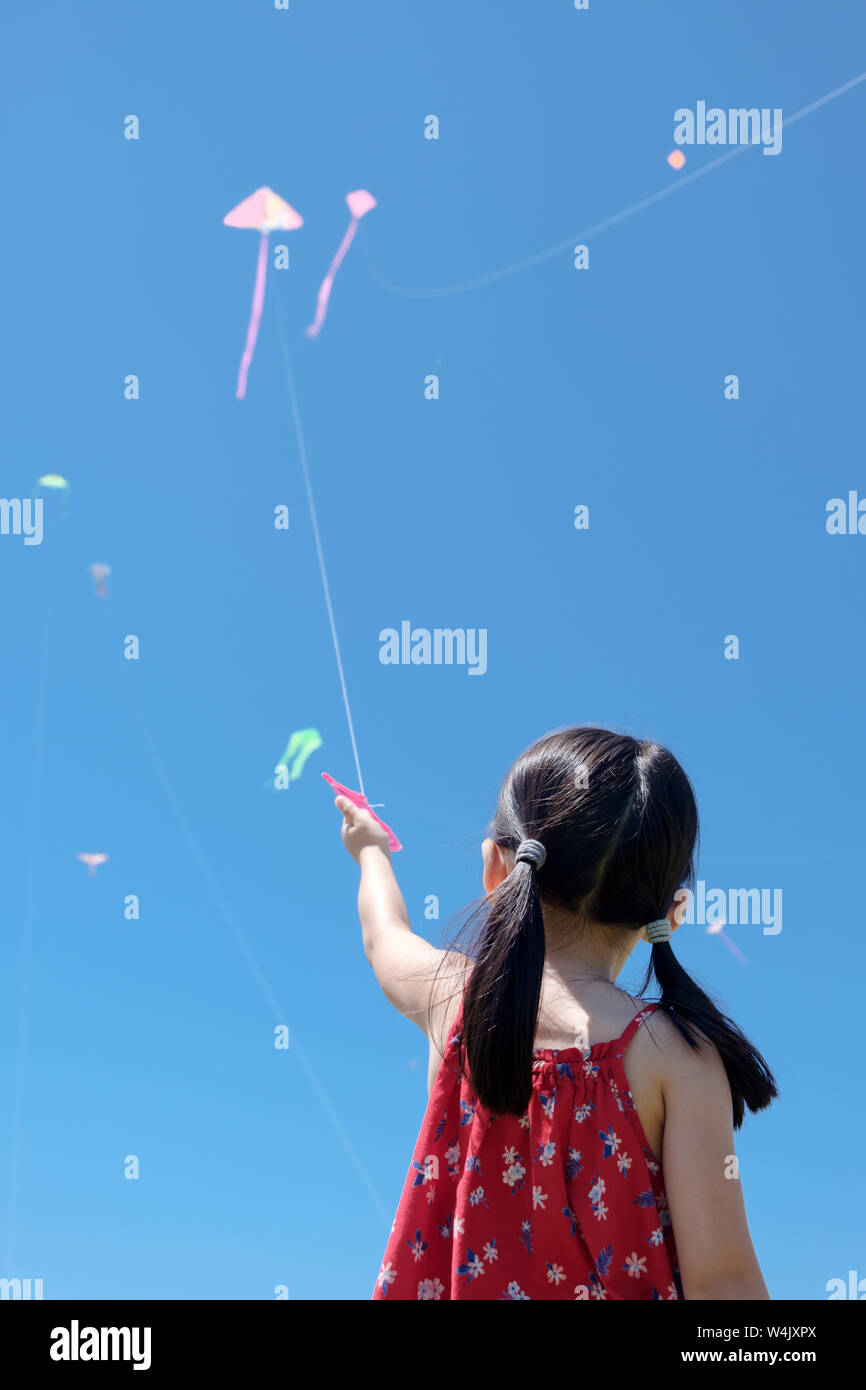 Kleines Mädchen flying a Kite in sonnigen Sommertag Stockfoto