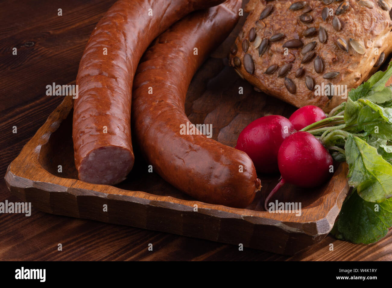 Geräucherte Wurst mit Brot und Rettich, rustikal essen auf einem Holztisch. Stockfoto