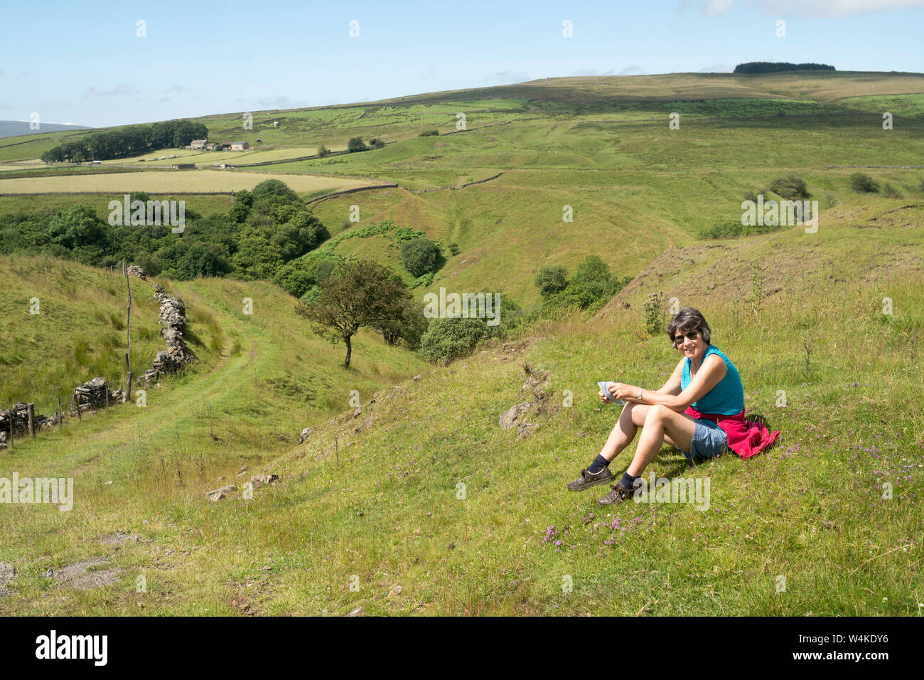 Attraktive ältere Frau bei einem Spaziergang über Westgate ruhend, in der North Pennines, gewohnt, Co Durham, England, Großbritannien Stockfoto