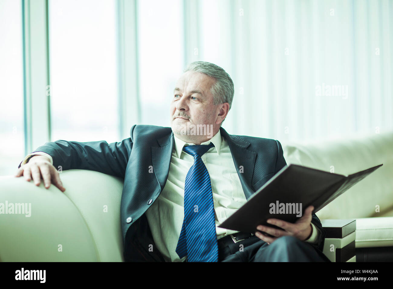 Erfolgreicher Geschäftsmann mit Geschäftsdokumenten sitzen auf einem Sofa in ein eigenes Büro Stockfoto