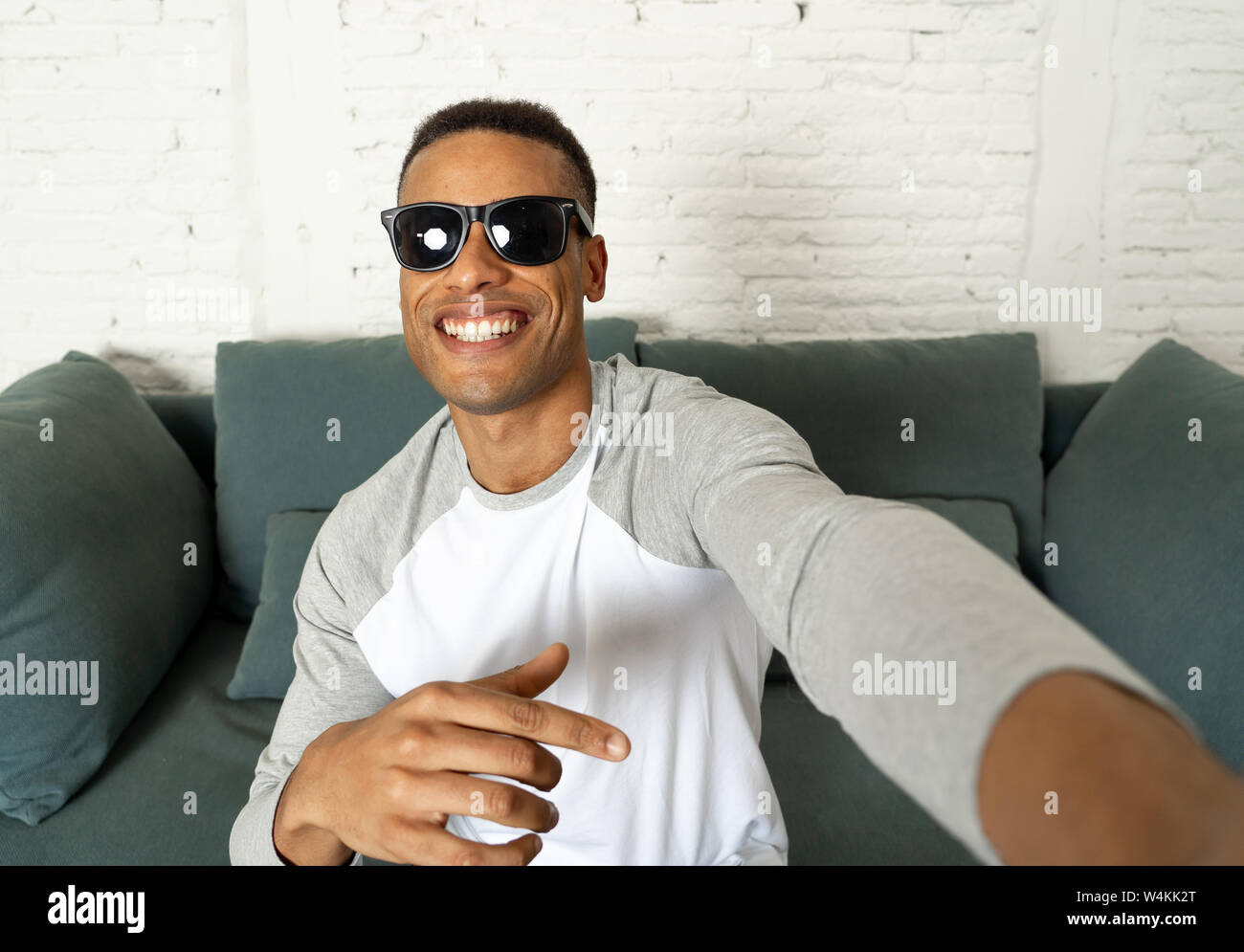 Junge attraktive afrikanische amerikanische Blogger Mann in modernen lässigen Stil holding Kamera oder Smart Phone schießen self portrait oder Aufnahme von Video für seine f Stockfoto