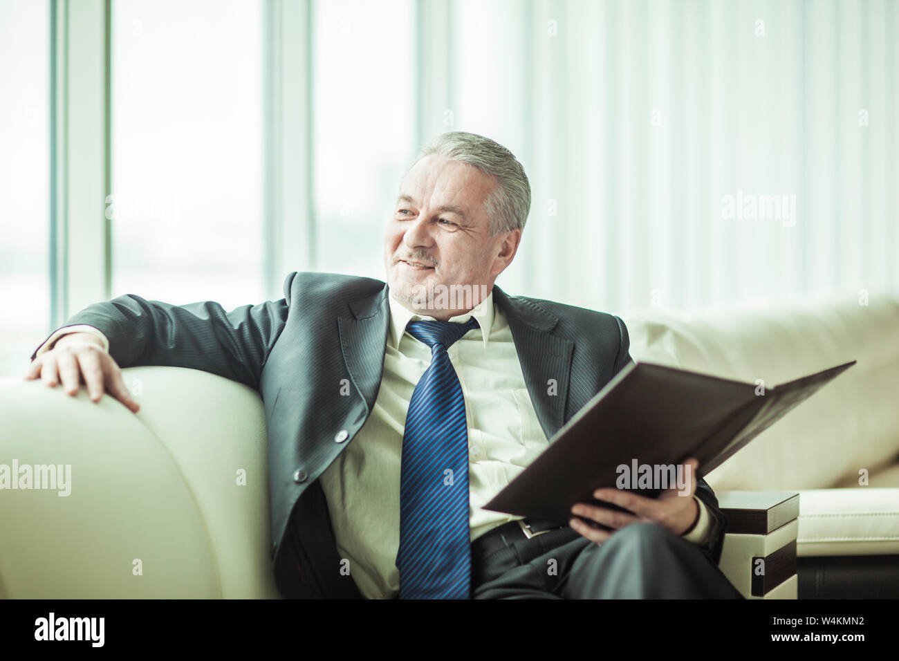 Erfolgreicher Geschäftsmann mit Geschäftsdokumenten sitzen auf einem Sofa in ein eigenes Büro Stockfoto