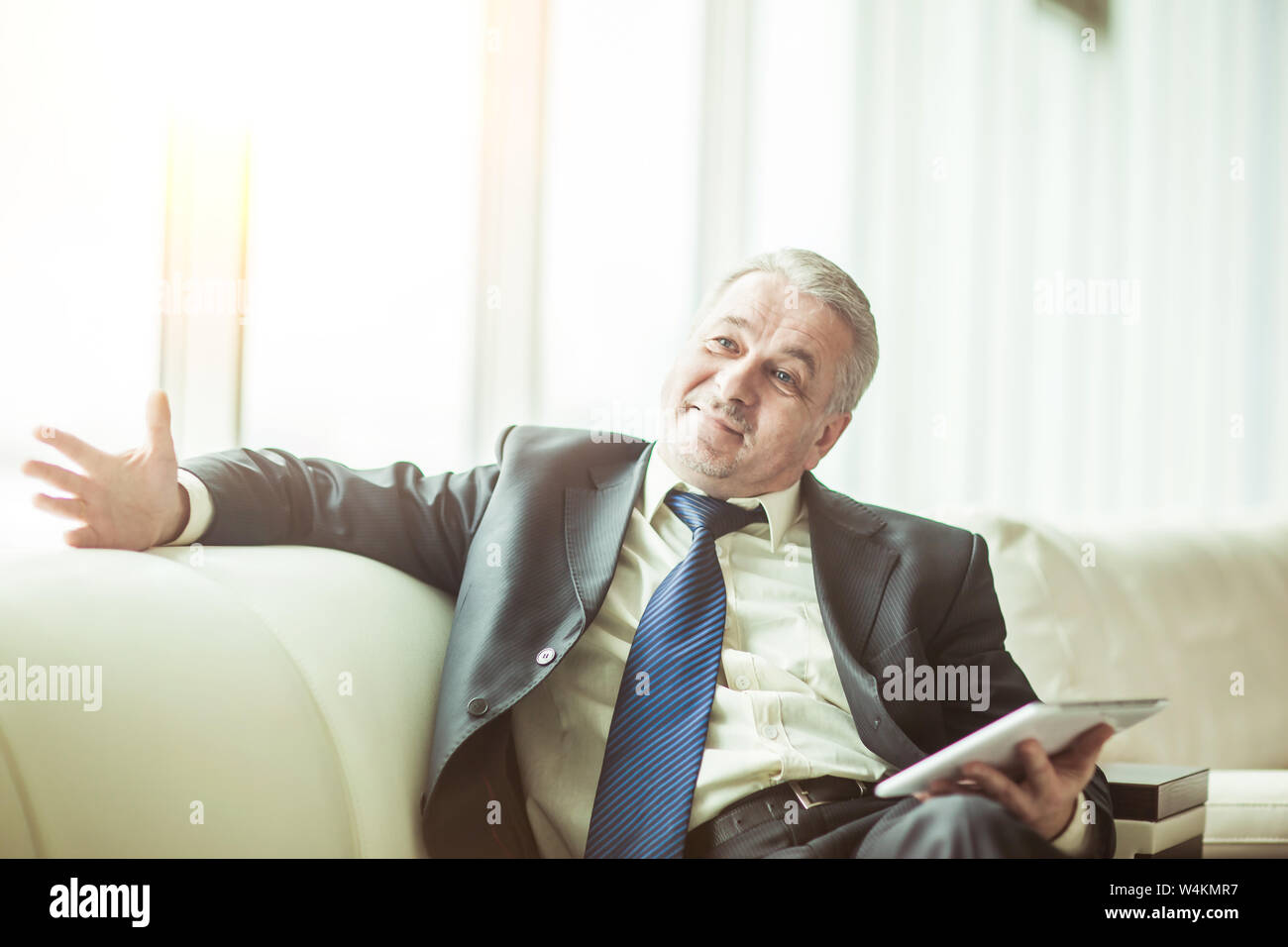 Erfahrene Unternehmer mit digitalen Tablet auf dem Sofa sitzen im eigenen Büro. Stockfoto