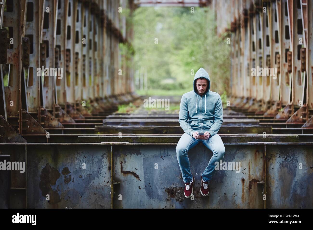 Einsamer Mann am Smartphone auf verlassenen rostige Brücke suchen. Stockfoto