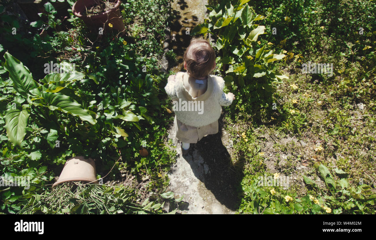 Baby Mädchen hinunter einen überwucherten Garten Pfad Stockfoto