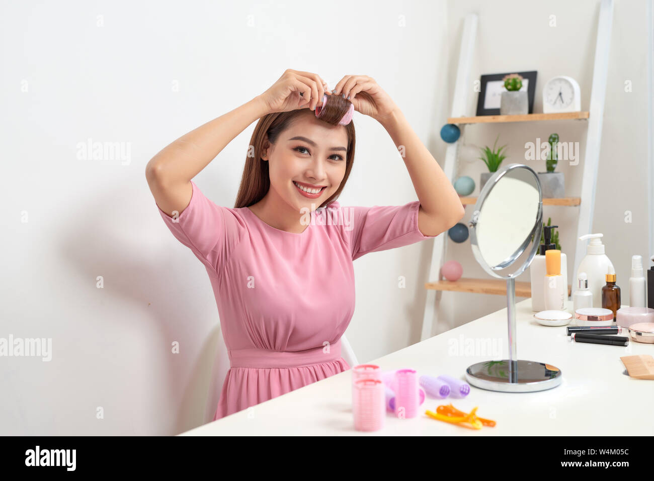 Kopf und Schultern Portrait von schöne asiatische Frau Haar Lockenwickler in Spiegel mit breitem Lächeln suchen, Home Interior auf Hintergrund Stockfoto