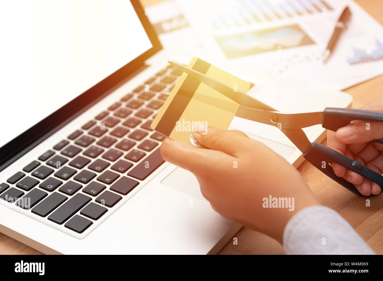 Frau verwenden Sie eine Schere Kreditkarten in der Hand vor Computer laptop zu schneiden Stockfoto