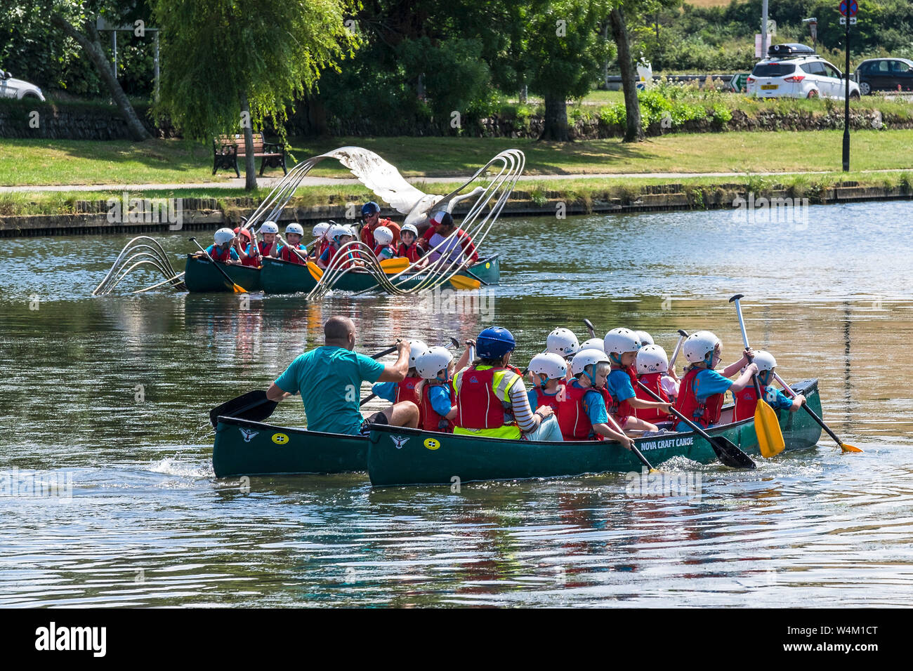 Grundschüler genießen einen freien Ausübung Aktivität Lektion, wie sie Spaß haben, Kanufahren auf trenance Garten See zum Bootfahren in Newquay in Cornwall. Stockfoto