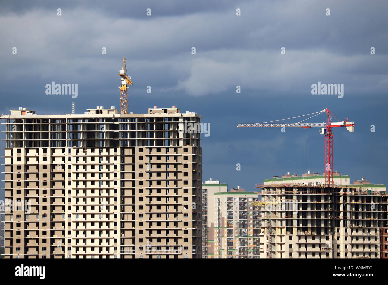Baukräne und hohe Wohn- Gebäude im Bau auf dem Hintergrund der Sturm Himmel mit Wolken Stockfoto