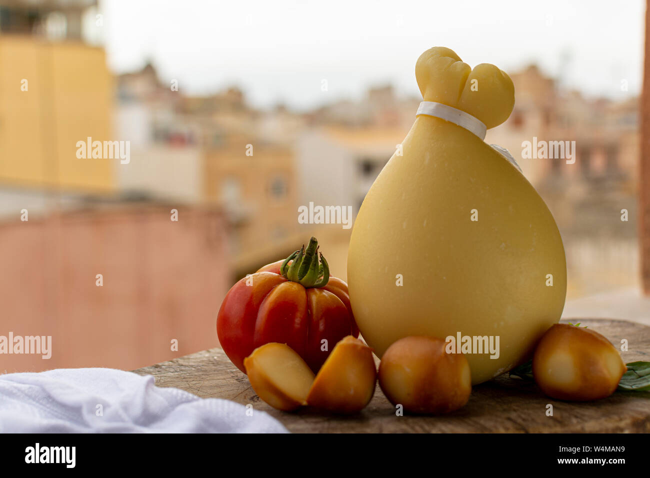 Käse, italienischen Provolone Caciocavallo gealtert und geräuchertem Käse in teardrop Form mit gelben houises der alten italienischen Stadt auf Hintergrund Stockfoto