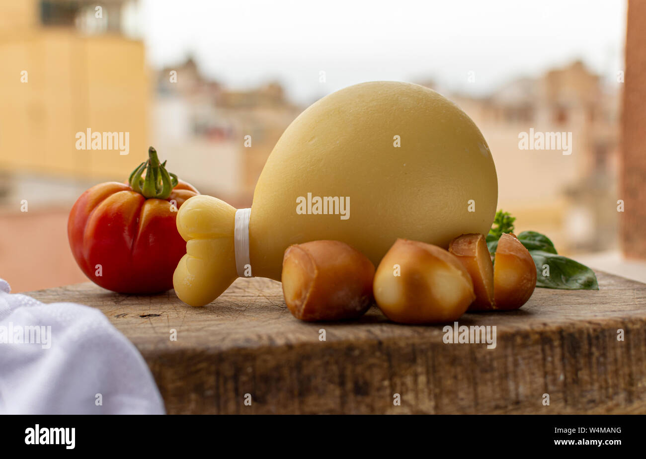 Käse, italienischen Provolone Caciocavallo gealtert und geräuchertem Käse in teardrop Form mit gelben houises der alten italienischen Stadt auf Hintergrund Stockfoto