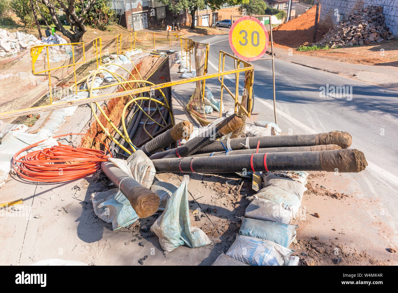 Straßenbau Erdbau tief graben mit Schutz Jalousien und Sandsäcke für neue Strom- Kabel installation Infrastruktur Stockfoto