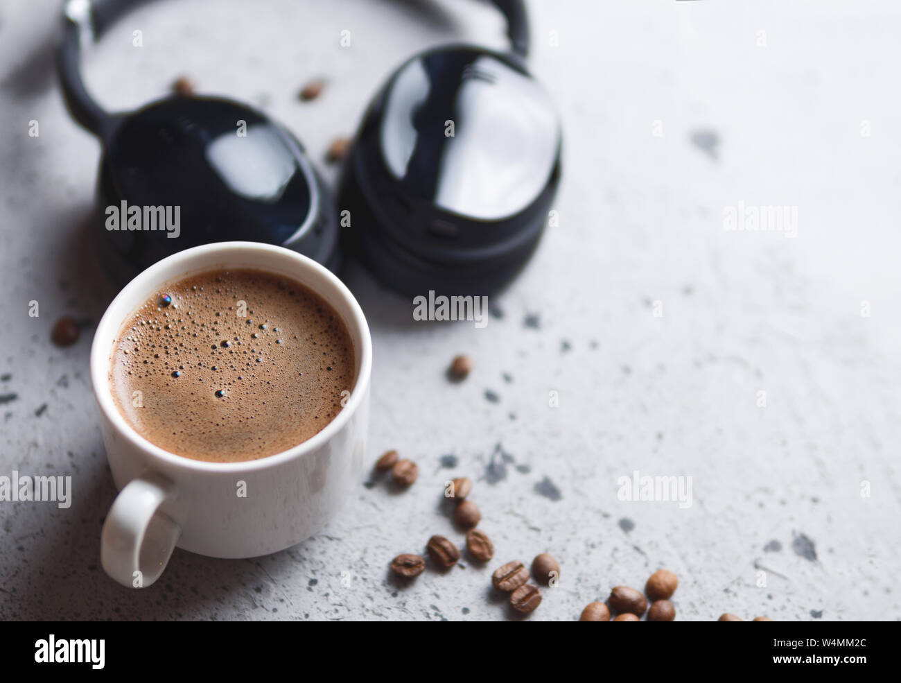 Weiße Tasse Espresso und Kopfhörer auf der konkreten Tabelle. Hörbuch und Podcast Stockfoto