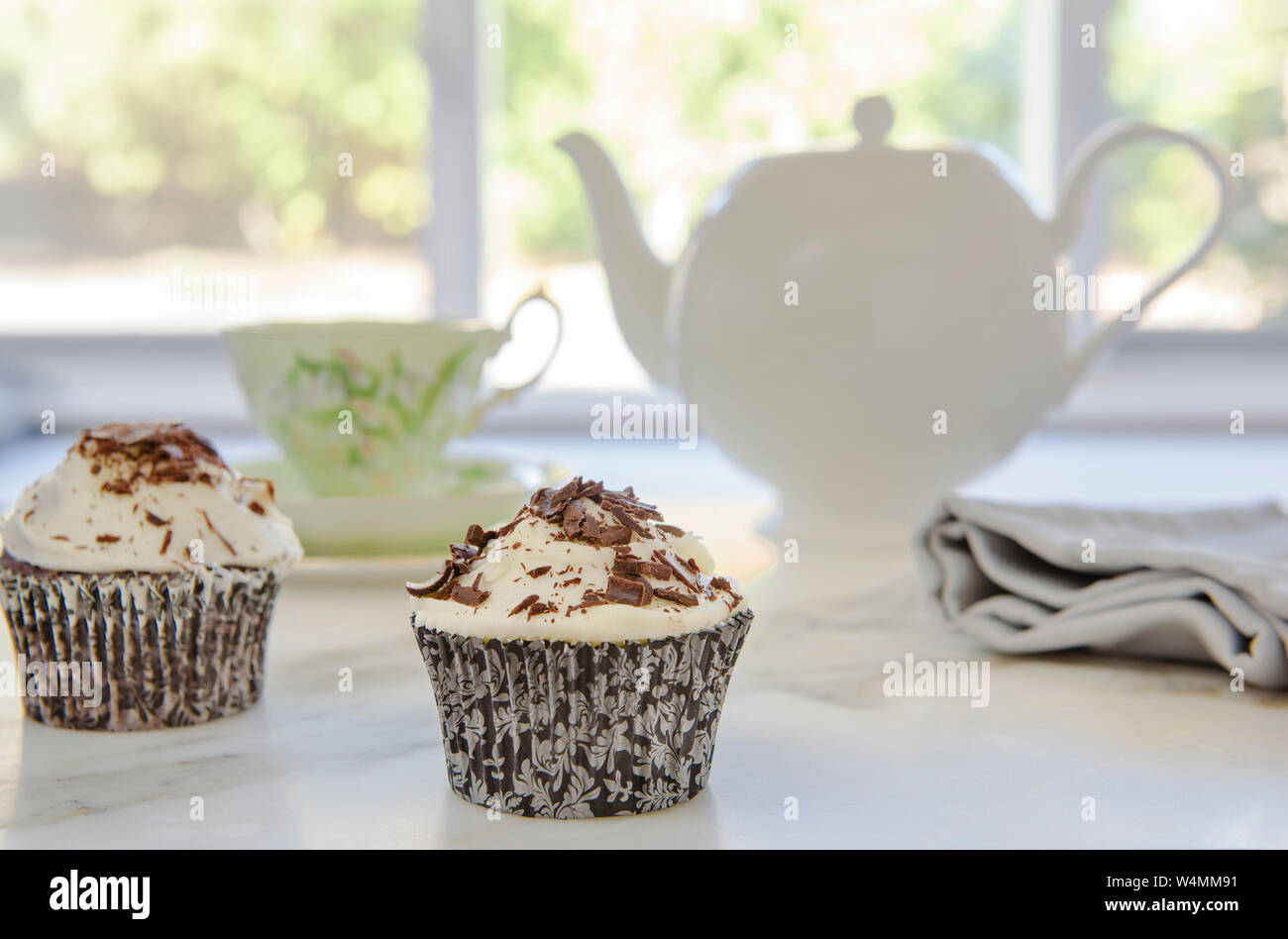 Eisschokolade Cupcakes mit Teekanne und Tasse im Hintergrund für den Nachmittagstee Stockfoto