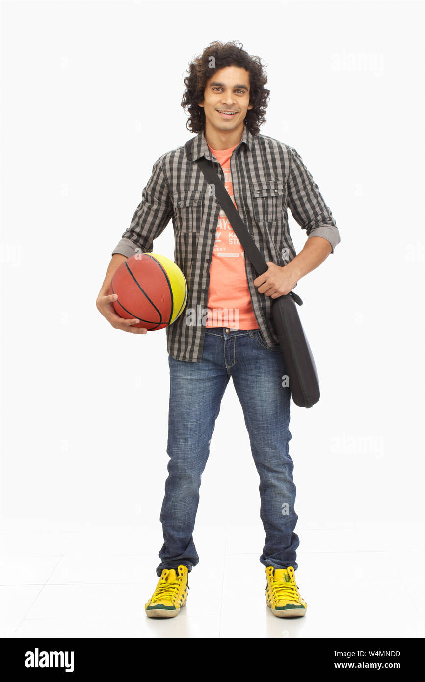 College Junge hält einen Basketball und lächelt Stockfoto