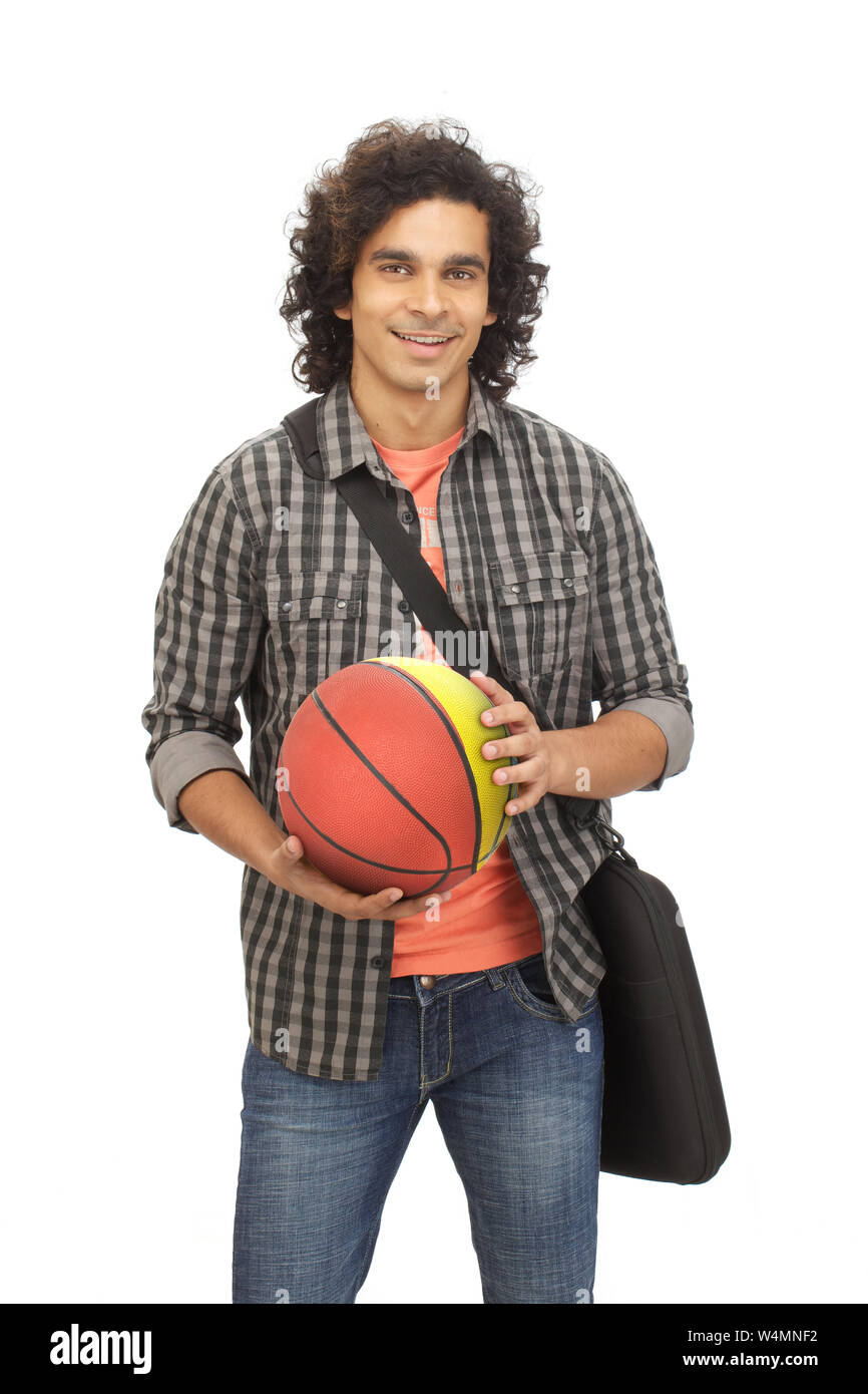 Junge indische College halten einen Basketball und lächelnd Stockfoto