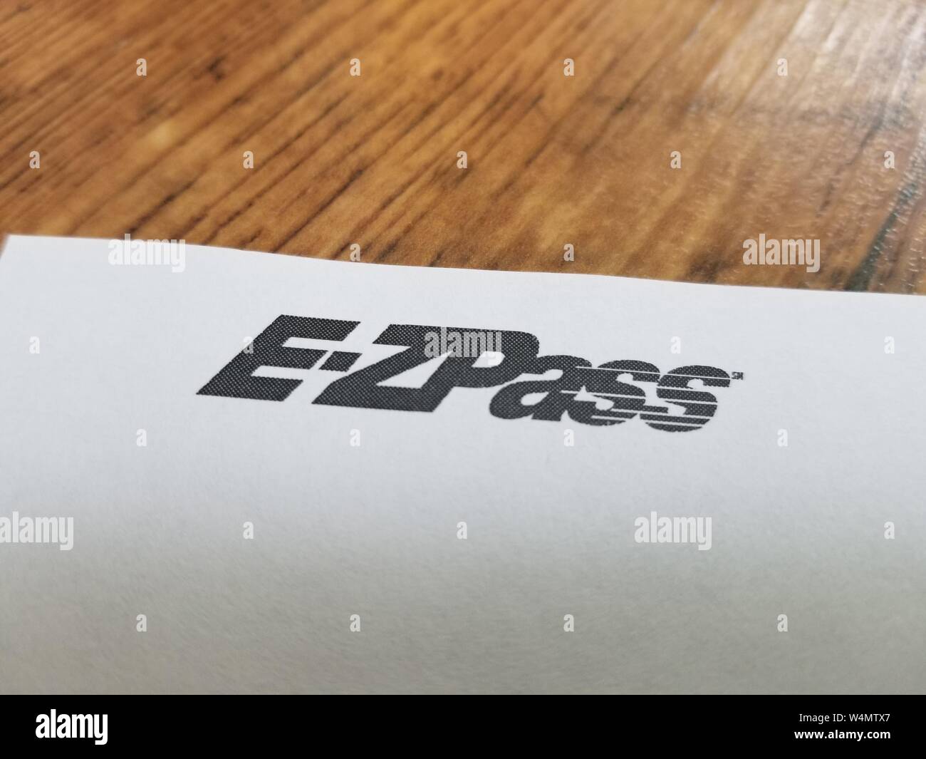 Close-up Logo für automatisierte Mautstelle agentur E-ZPass, den nordöstlichen Vereinigten Staaten dienen, auf weissem Papier vor einem hellen Holz- Oberfläche, 7. Juli 2019. () Stockfoto