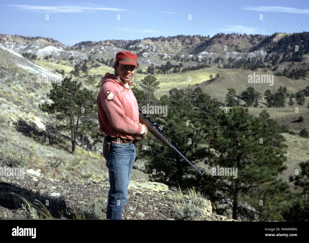 Jäger tragen hohe Sichtbarkeit Outfit und stehen mit einer Schrotflinte auf einer Klippe, 1965. () Stockfoto