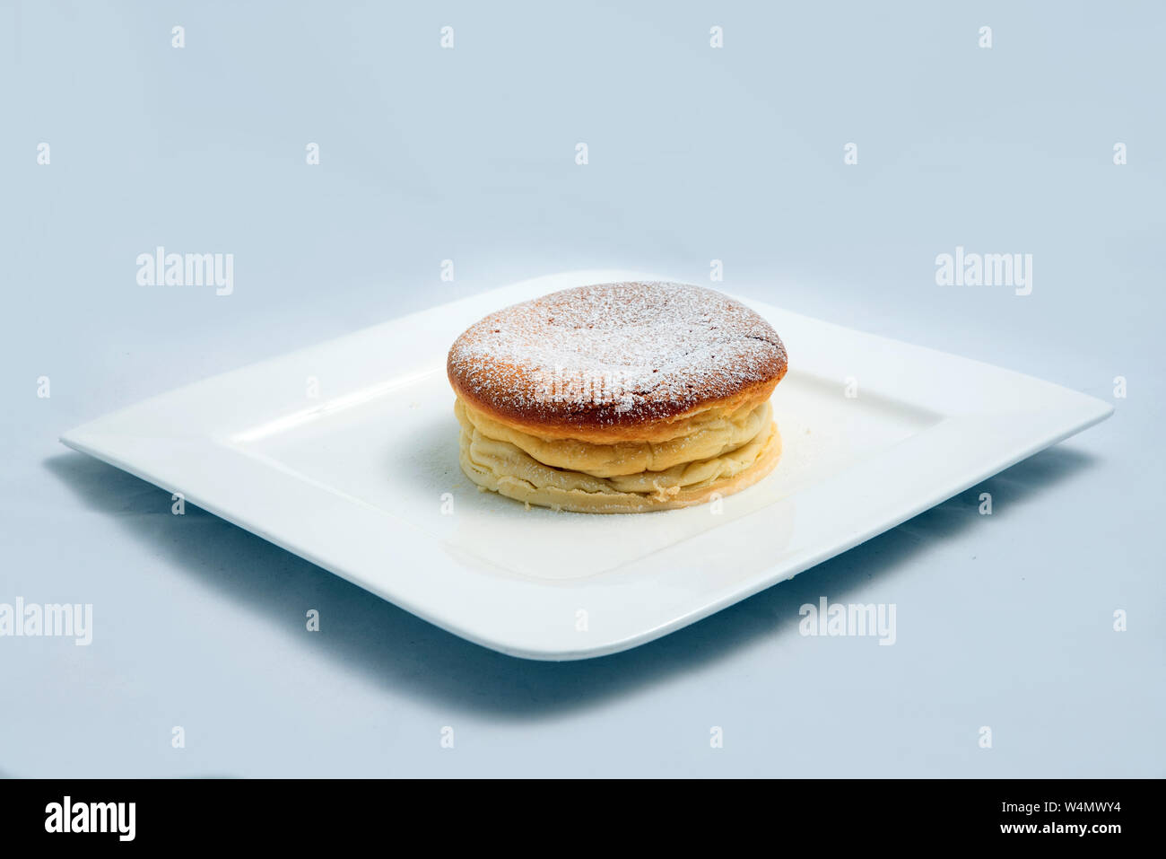 Einen niedrigen Kontrast hero Schuß eines Pan Kuchen auf den Teller, auf einen minimalen weißen Hintergrund mit einer Diagonale von 60 Grad Stockfoto